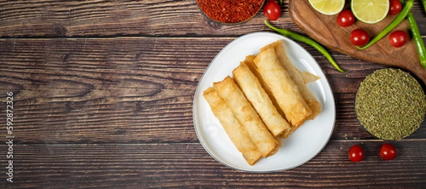 Fototapeta Cigarette pastry. Cheese pie on wood floor. Fried cheese rolls with phyllo. Local name sigara boregi. Top view. Empty space for text. copy space