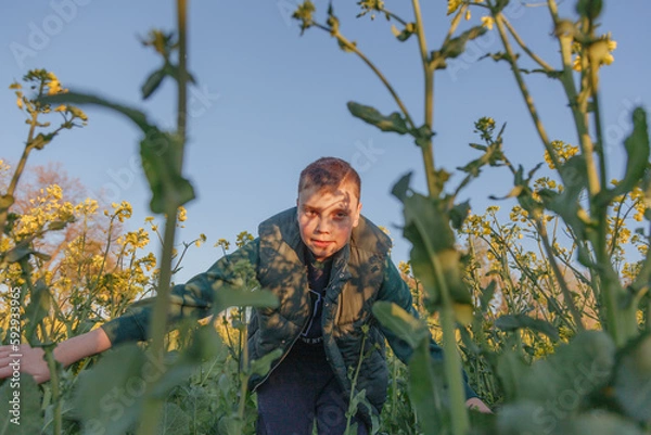 Fototapeta boy looks at the ground in a field of flowers