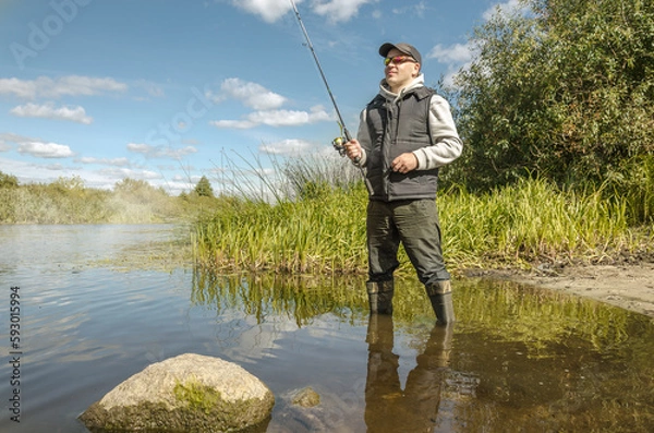 Obraz Fisherman in a hat on the river bank