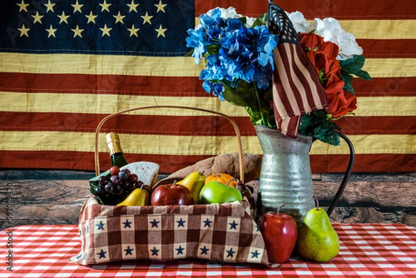Obraz picnic basket on checkered table cloth bouquet of flowers and American flag background