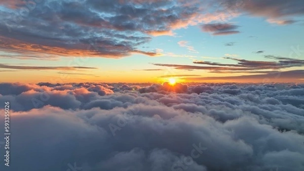 Fototapeta Epic sunset over the clouds. Flight in the sky at sunset, view from window of airplane. Warm sun sets over the horizon in clouds