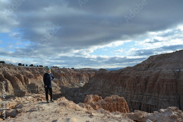 Fototapeta woman in the Cathedral Gorge State Park on a cold day in December, located in a long, narrow valley in southeastern Nevada, where erosion has carved patterns in bentonite clay