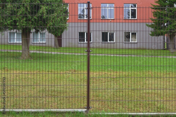 Fototapeta New metal lattice fence on the background of the building.