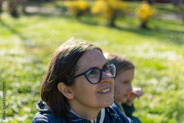 Fototapeta A portrait of mother with a small daughter in spring nature at sunset.