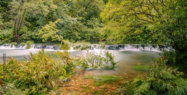 Fototapeta Panoramic landscape of the recreational area of ​​Ponte Segade, La Coruña, with a waterfall on the Sor river, surrounded by green vegetation, leaves and transparent water in summer of 2021 Spain