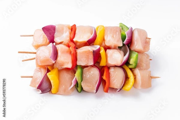 Obraz Raw chicken skewers with vegetables, peppers, onions, on a white background.Uncooked mixed meat skewer with peppers.Skewers with pieces of raw meat, red, yellow and green pepper.Top view.