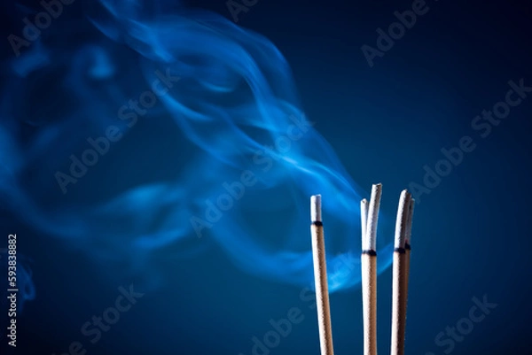 Fototapeta Incense sticks and incense stick smoke on black backgrond with white backlit