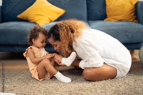 Fototapeta mother is taking care of her daughter by covering a wound or scrape on her knee with a plastic bandage to help reducing the risk of infection and allowing the wound to heal more quickly.