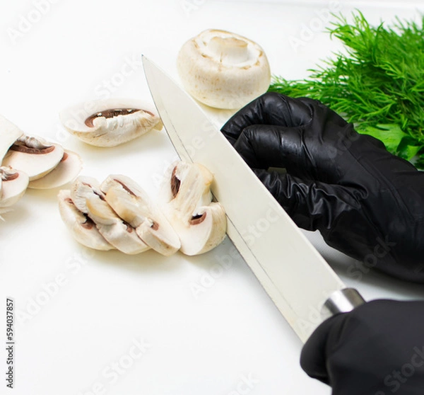 Fototapeta Hands of cook in black rubber gloves cut mushrooms with knife