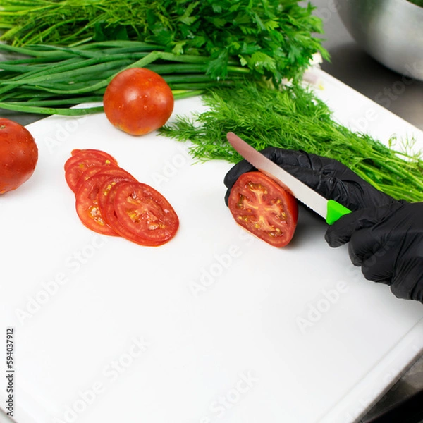 Obraz Hands of cook in black rubber gloves cuts tomatoes