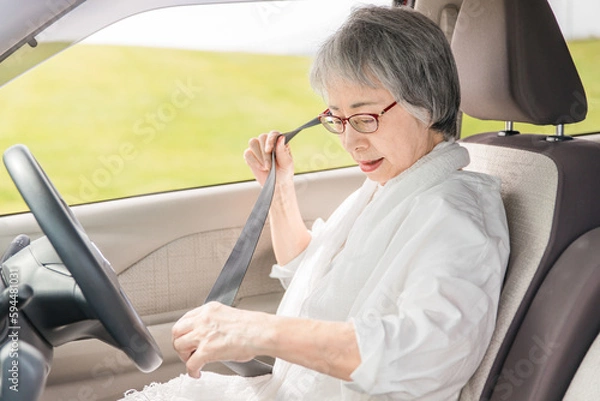 Obraz 自動車の運転席に乗りシートベルトを締めるアジア人の高齢者ドライバー
