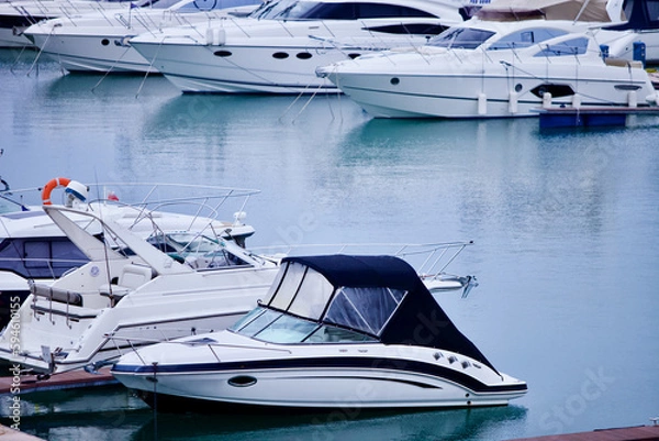 Fototapeta Yachts and speed boats at harbor. Yachts moored in the port. Ocean Coast pier. High class lifestyle. Yachting. Expensive toys. Sea ​​transport. Nautical. Yachting sport. Expensive yachts at the pier.