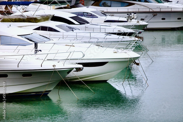 Fototapeta Yachts and speed boats at harbor. Yachts moored in the port. Ocean Coast pier. High class lifestyle. Yachting. Expensive toys. Sea ​​transport. Nautical. Yachting sport. Expensive yachts at the pier.