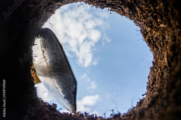 Fototapeta Digging garden pits for planting plants. View from a freshly dug pit full of clay. View from below.