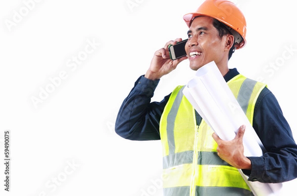 Obraz Smiling engineer holding blueprint talking on the phone