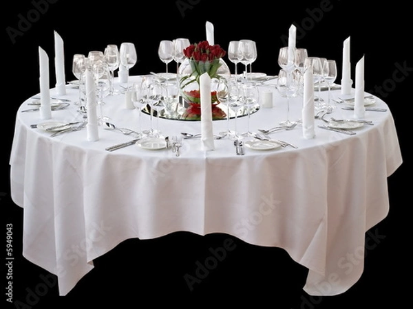 Fototapeta festlicher Esstisch mit weißer Tischdecke, Servietten und Blumenarrangement mit roten Rosen freigestellt auf schwarzem Hintergrund