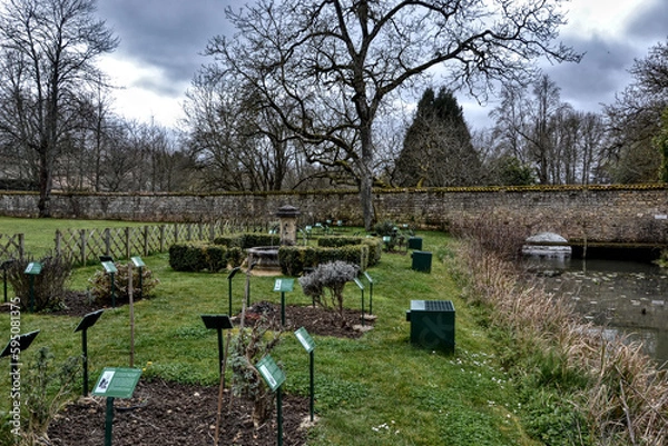 Fototapeta Nouaillé-Maupertuis, France - March 25th 2016 : Saint-Junien abbey. It is a fortified Benedictine abbey. It was built in the 9th century. Focus on the garden, medieval type, with period plants.