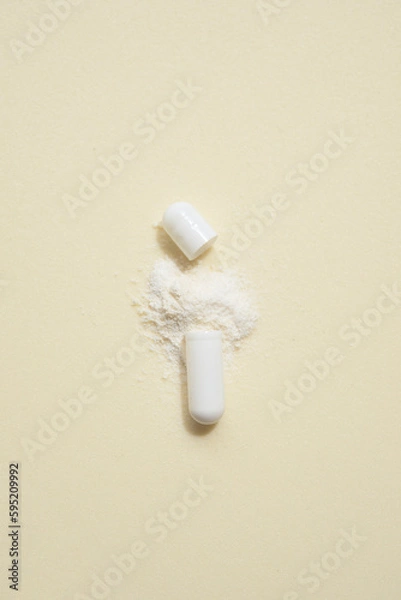 Obraz opened capsule showing supplement powder on beige colour background