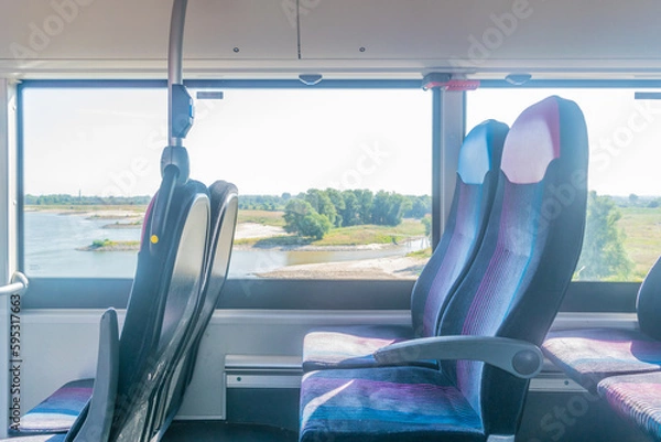 Fototapeta Side view of Empty seats at a european bus driving next to A river in a Dutch polder landscape