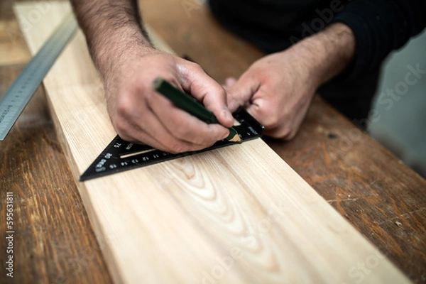 Fototapeta Carpenter holding a set square on the work bench