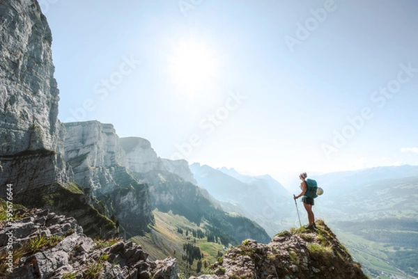 Obraz A sporty woman enjoys the  amazing view from a vantage point on churfürsten mountain range in the morning. Schnürliweg, Walensee, St. Gallen, Switzerland, Europe.