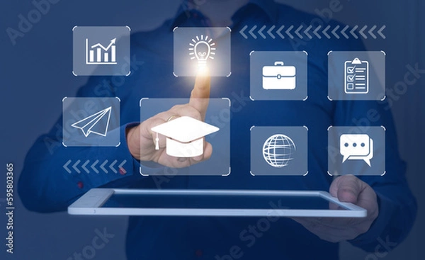 Fototapeta Icons of online education, planet, airplane and idea on tablet with hand of businessman. Male uses tablet to study lessons on Internet, concept of e-learning, online courses.