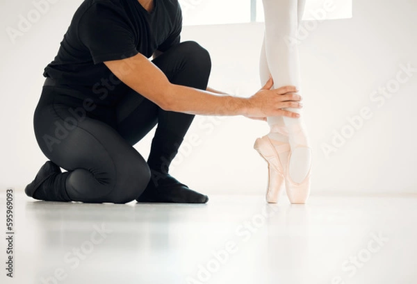Fototapeta Ballet is an art form all about precision. Closeup shot of a ballet teacher assisting a student with her position in a dance studio.