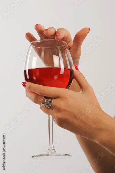 Obraz Woman's hand holding a glass of red wine on a white background