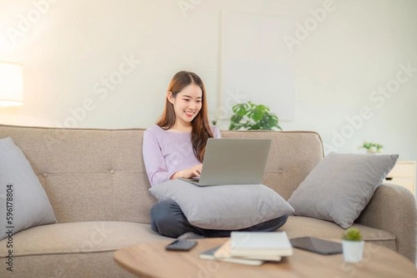 Obraz Young woman working on her notebook computer at her home. Work from home concept.