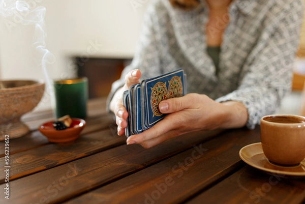 Fototapeta Fortune teller with tarot cards on table near burning candle.Tarot cards spread on table with magic herbs and palo santo aroma sticks. Forecasting concept