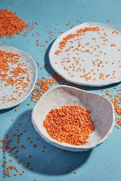 Fototapeta Lens culinaris is scientific name of Turkish Red Lentil legume. Also known as Lentilha Vermelha (portuguese). Top view of grains in a glass. White and blue background.