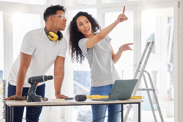 Fototapeta From concept to planning. Shot of a young couple using a laptop while busy renovating a house.