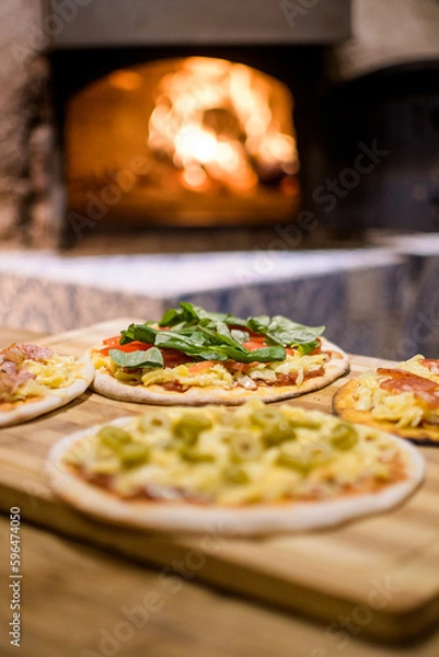 Fototapeta small individual pizzas ready to be introduced into the clay oven with its fire inside
