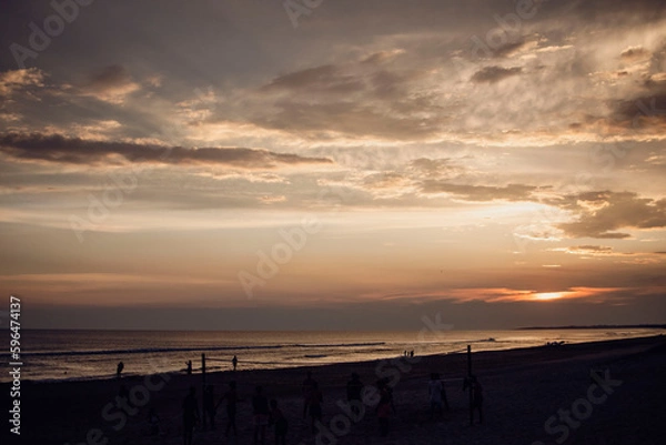 Fototapeta Sunset in summer vacation on the beach, with clouds in the sky. View from the seashore near the sand
