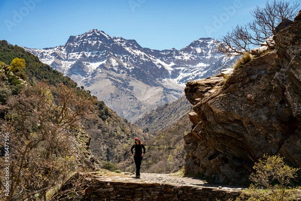 Obraz Woman hiking in Vereda de la Estrella. Peaks of Sierra Nevada National Park in the background (Alcazaba, Mulhacén)