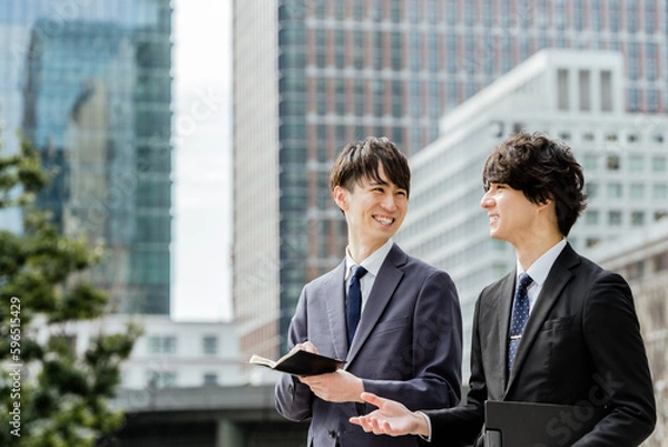 Obraz ビジネス街を歩きながら会話の弾む20代と30代の上司と部下の2人の男性ビジネスマン