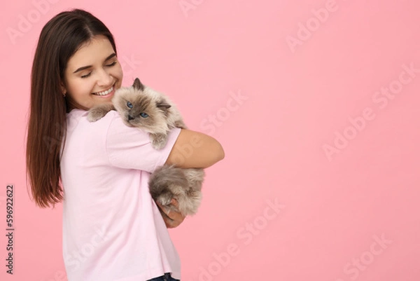 Fototapeta Happy woman hugging her cute cat on pink background, space for text