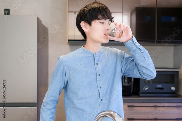 Obraz キッチンで水を飲む男性