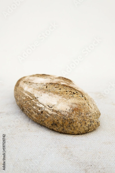 Fototapeta Baked bread of sourdough. Artisan bread on light background. The bread of sourdough, homemade and natural creation. 