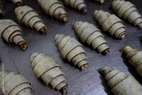 Fototapeta Close-up Layered of a fluffy leavened uncooked raw traditional French croissants dough roll in a baking Tray and preparing to cook in the oven. It's a buttery, flaky pastry.