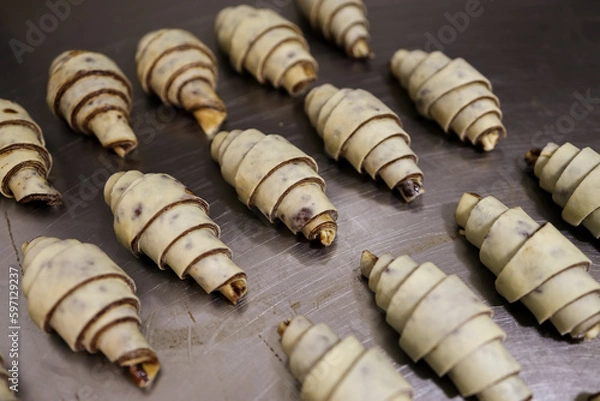 Fototapeta Close-up Layered of a fluffy leavened uncooked raw traditional French croissants dough roll in a baking Tray and preparing to cook in the oven. It's a buttery, flaky pastry.