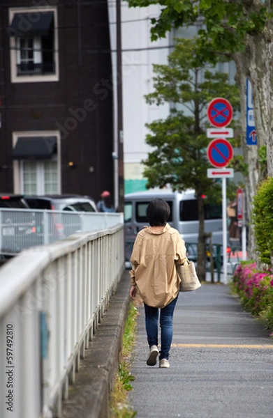Fototapeta 街の道路で歩く一人の女性の姿
