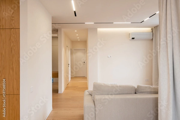 Fototapeta Bright living room interior with large sofa and oak wooden floor. Concept of minimalist design. Comfortable place for meeting.