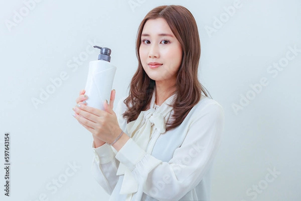 Fototapeta 白色のシャンプーを持ったカメラ目線の女性