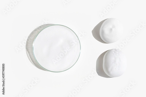 Obraz White foam in a Petri dish on a light background. Smears of foam on the background.