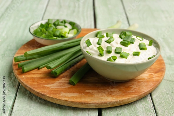 Fototapeta Bowl of tasty sour cream with green onion on light wooden background