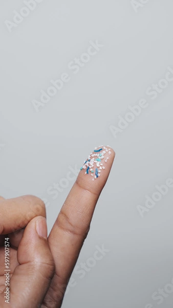 Fototapeta Climate change idea. Close up microplastics lay on female people finger hand. it's very small.