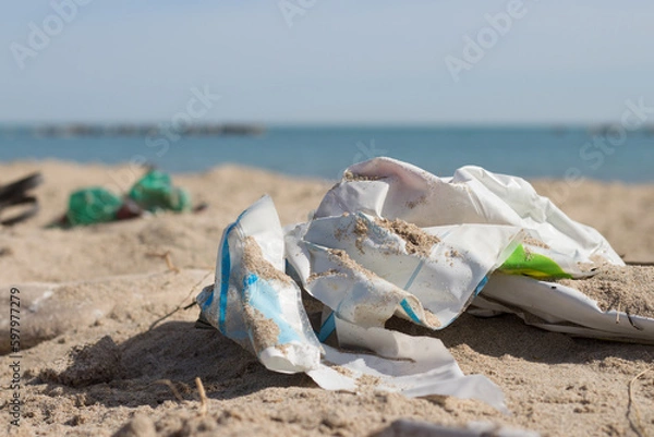 Obraz Spilled garbage on the beach of the big city. Plastic. Dirty sea. Environmental pollution. Ecological problem.