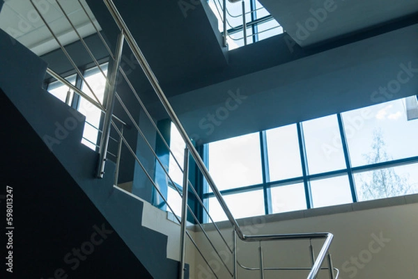 Fototapeta Stairs in a concrete office building in neutral tones, covered with ceramic tiles, with shiny metal railings