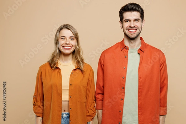 Fototapeta Young smiling happy fun satisfied caucasian cool couple two friends family man woman wear casual clothes looking camera together isolated on pastel plain light beige color background studio portrait.